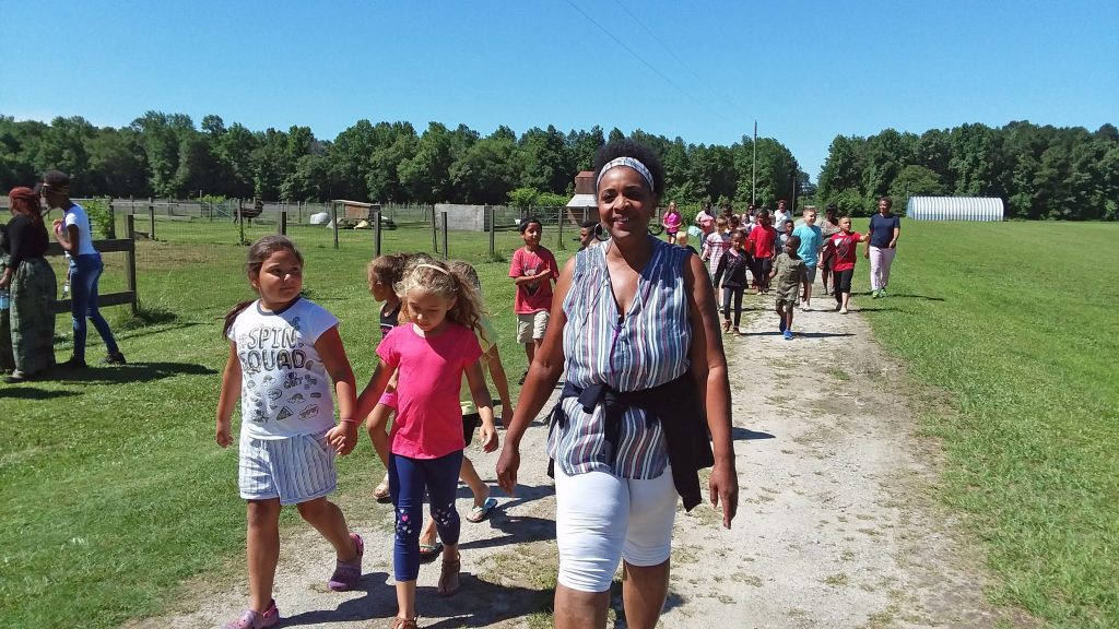 Hill Family Farm founder, Eunice, walks with a group of children on the farm grounds